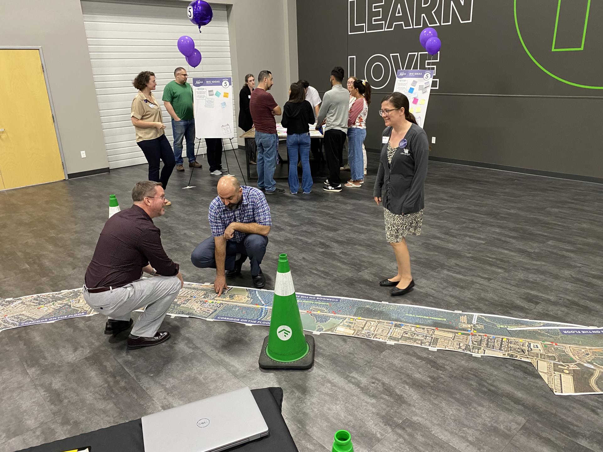 Two people kneel looking at the map of Business 121 on the floor